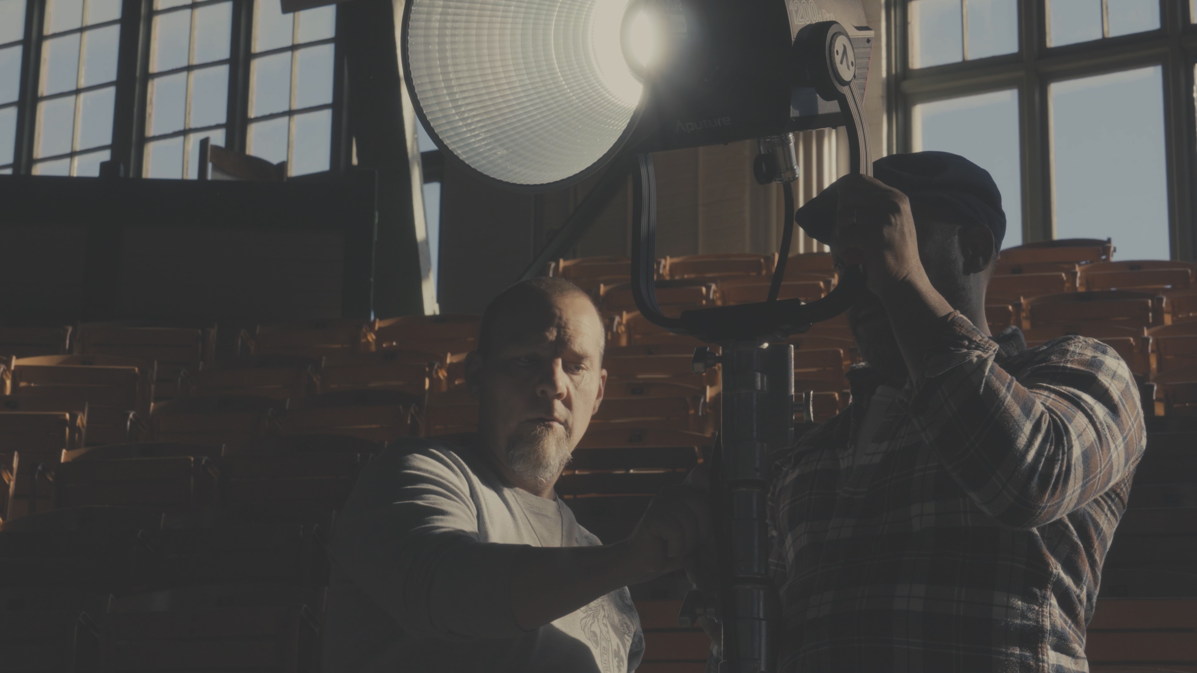 Two crew members adjusting a large LED light in the rodeo arena