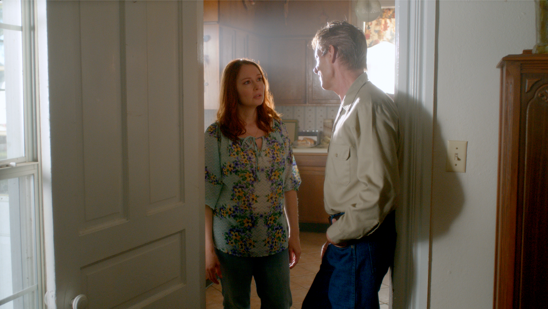 Woman in floral blouse and man facing each other in doorway
