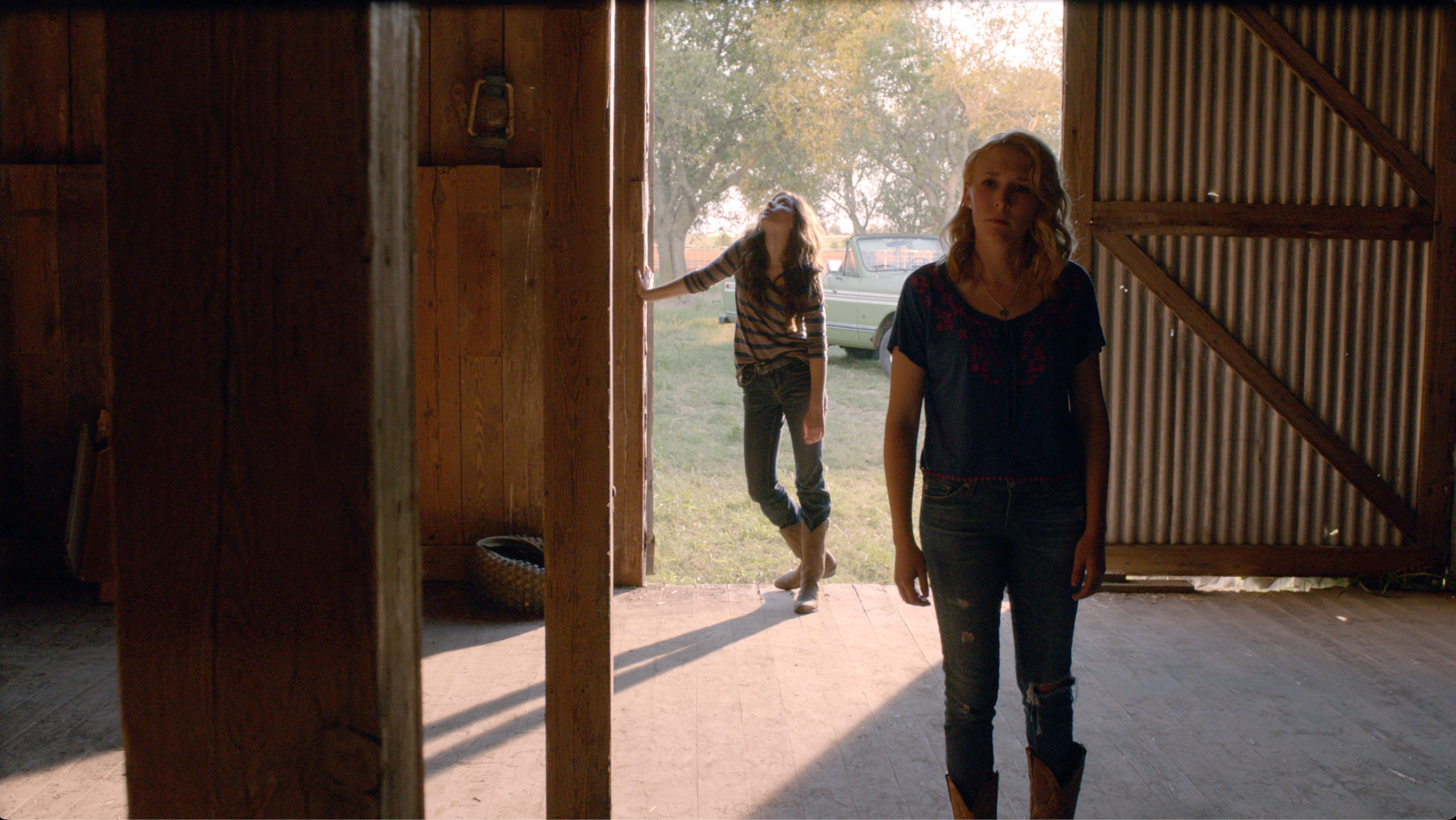 Two women in a barn doorway flooded with golden afternoon light