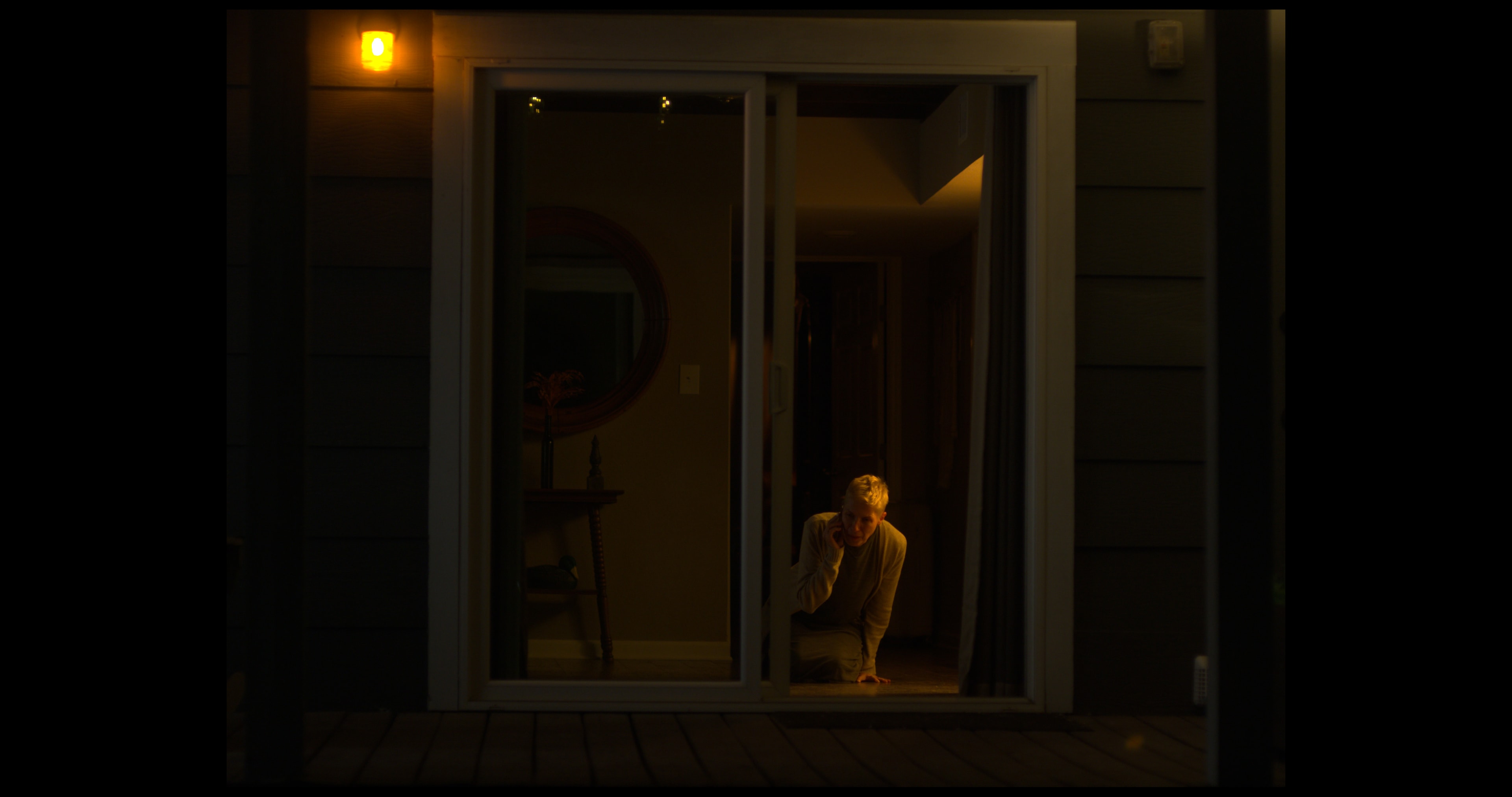 Character crouching at sliding glass door in the dark