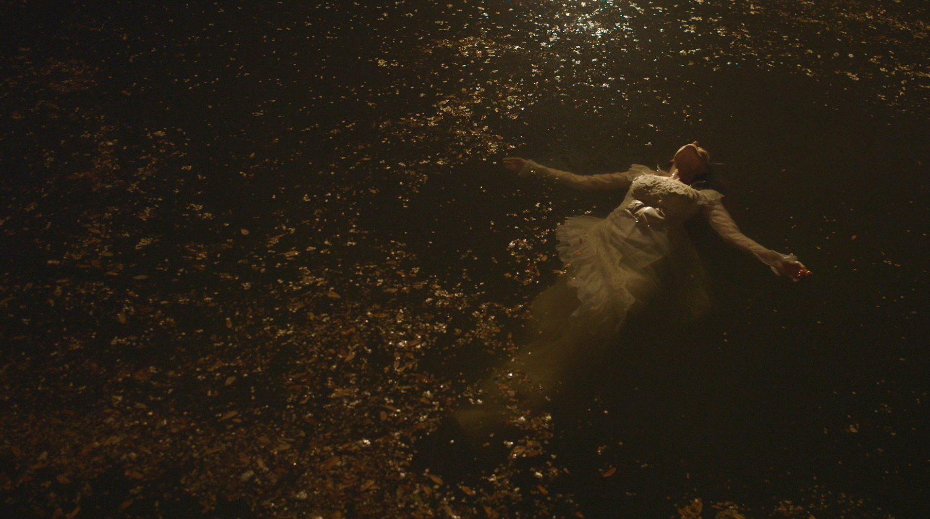 Figure in white dress floating among golden particles