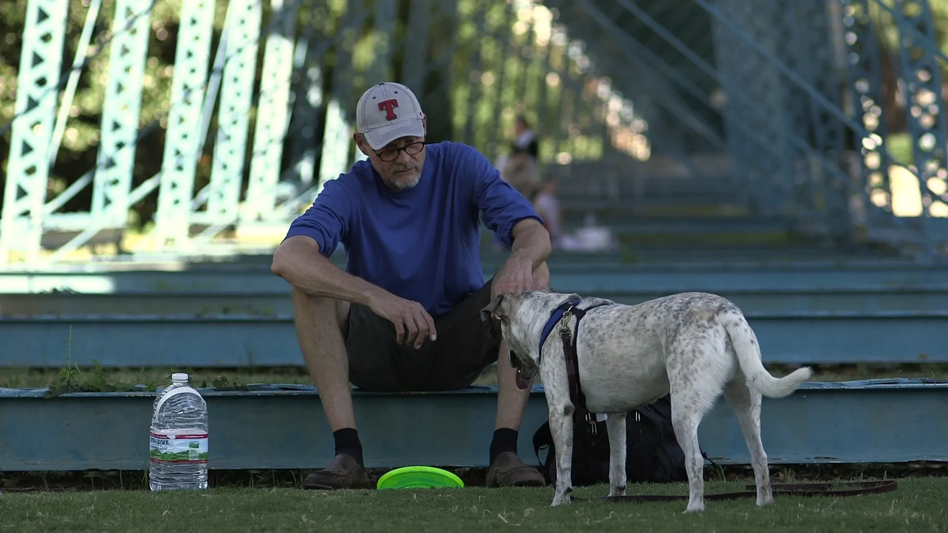 Man sitting with his dog by a bridge