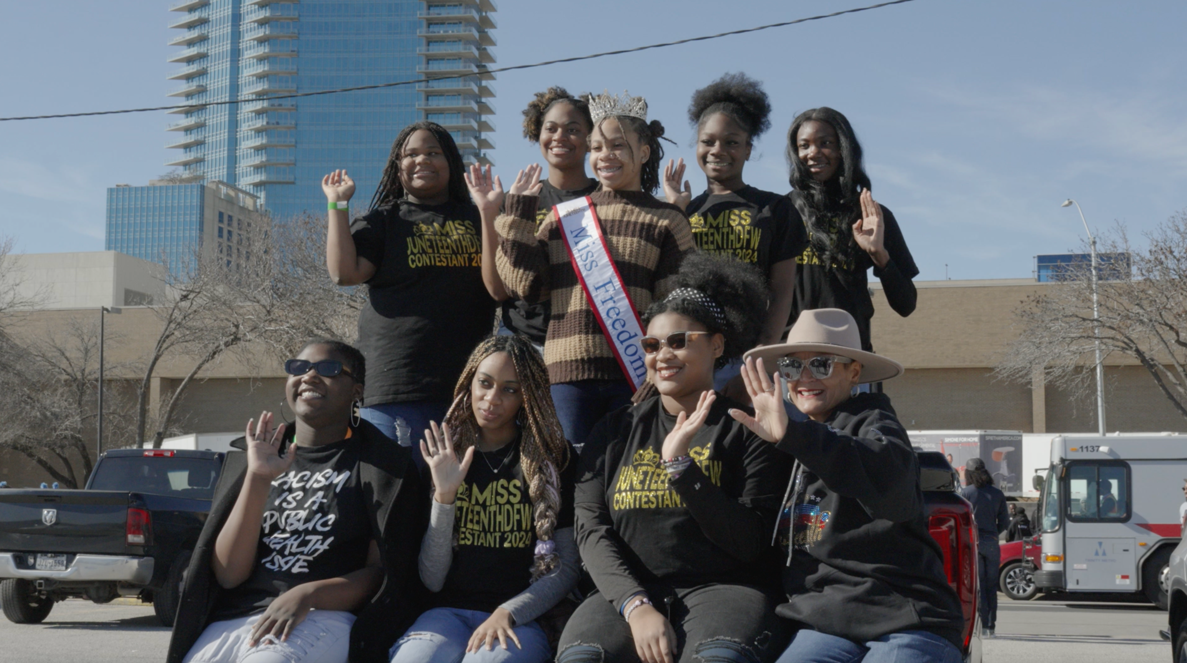 Miss Juneteenth DFW contestants waving from parade float