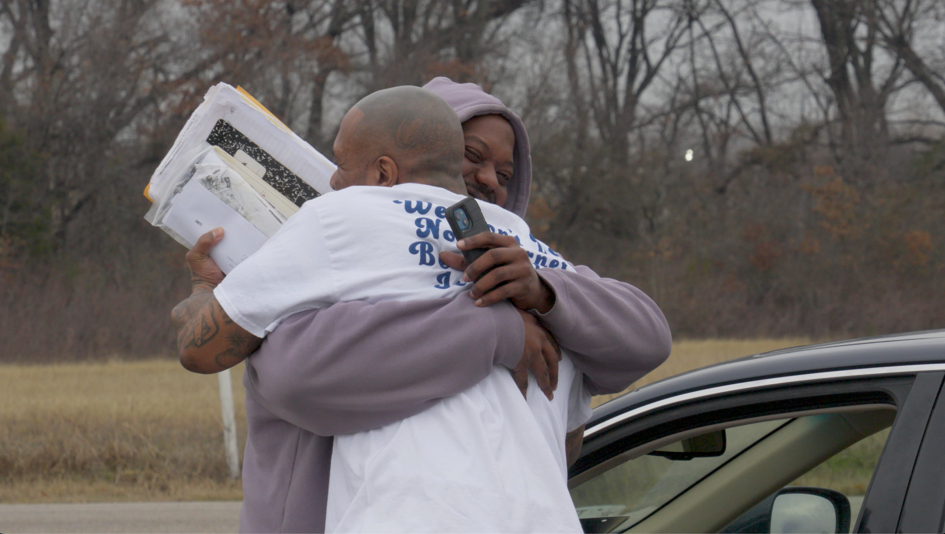 Two people embracing outdoors by a car