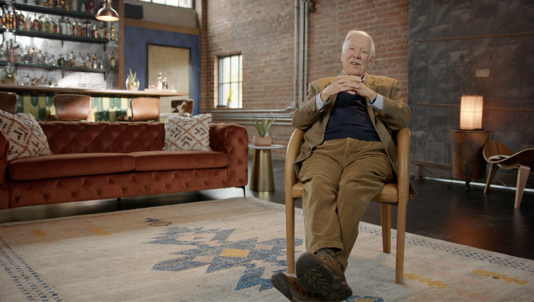 Older man in tan blazer seated in upscale brick loft