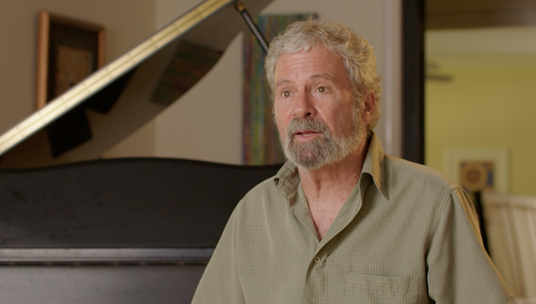 Musician in green shirt seated at grand piano close-up