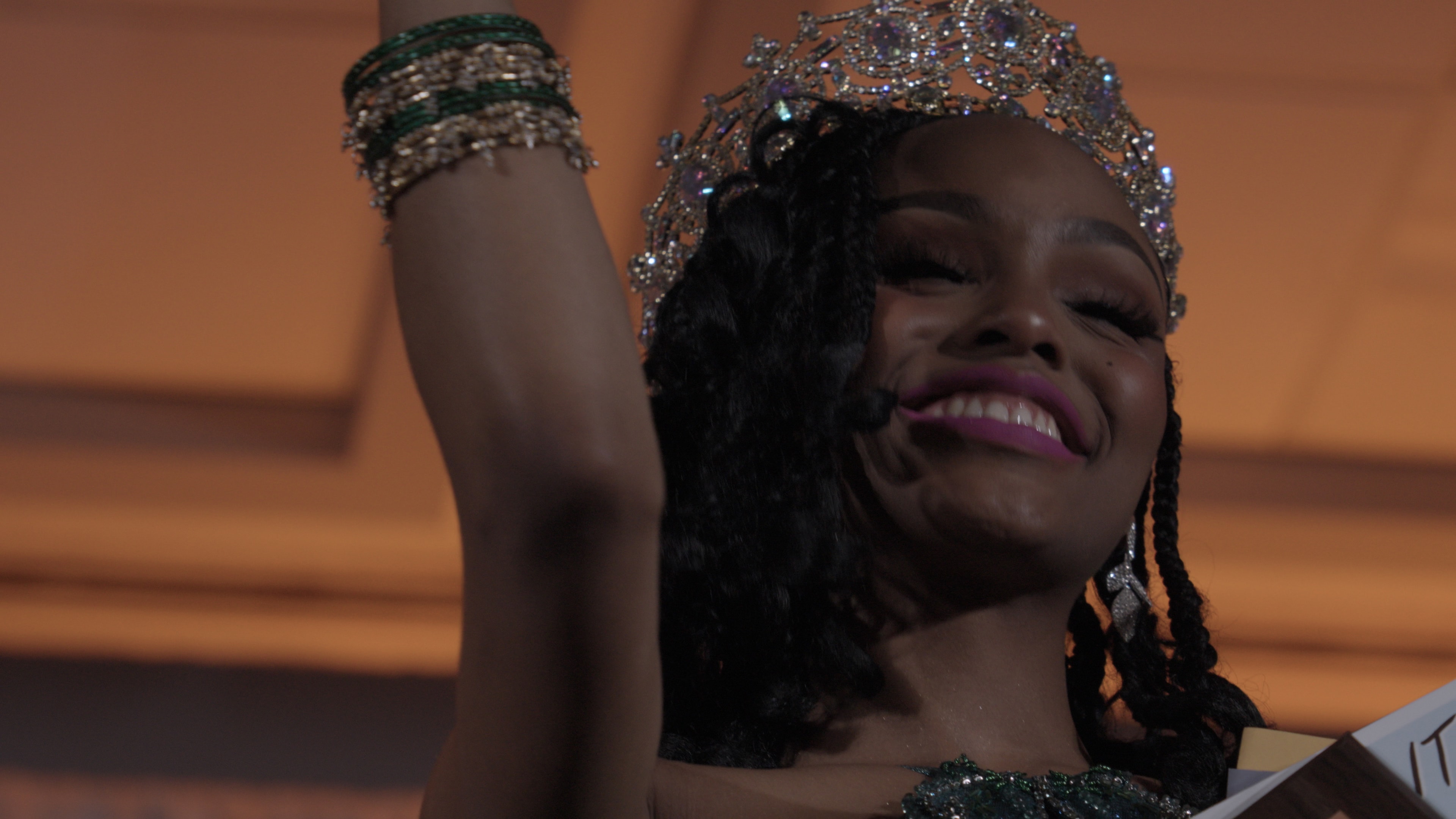 Woman in crown and jewels celebrating on stage