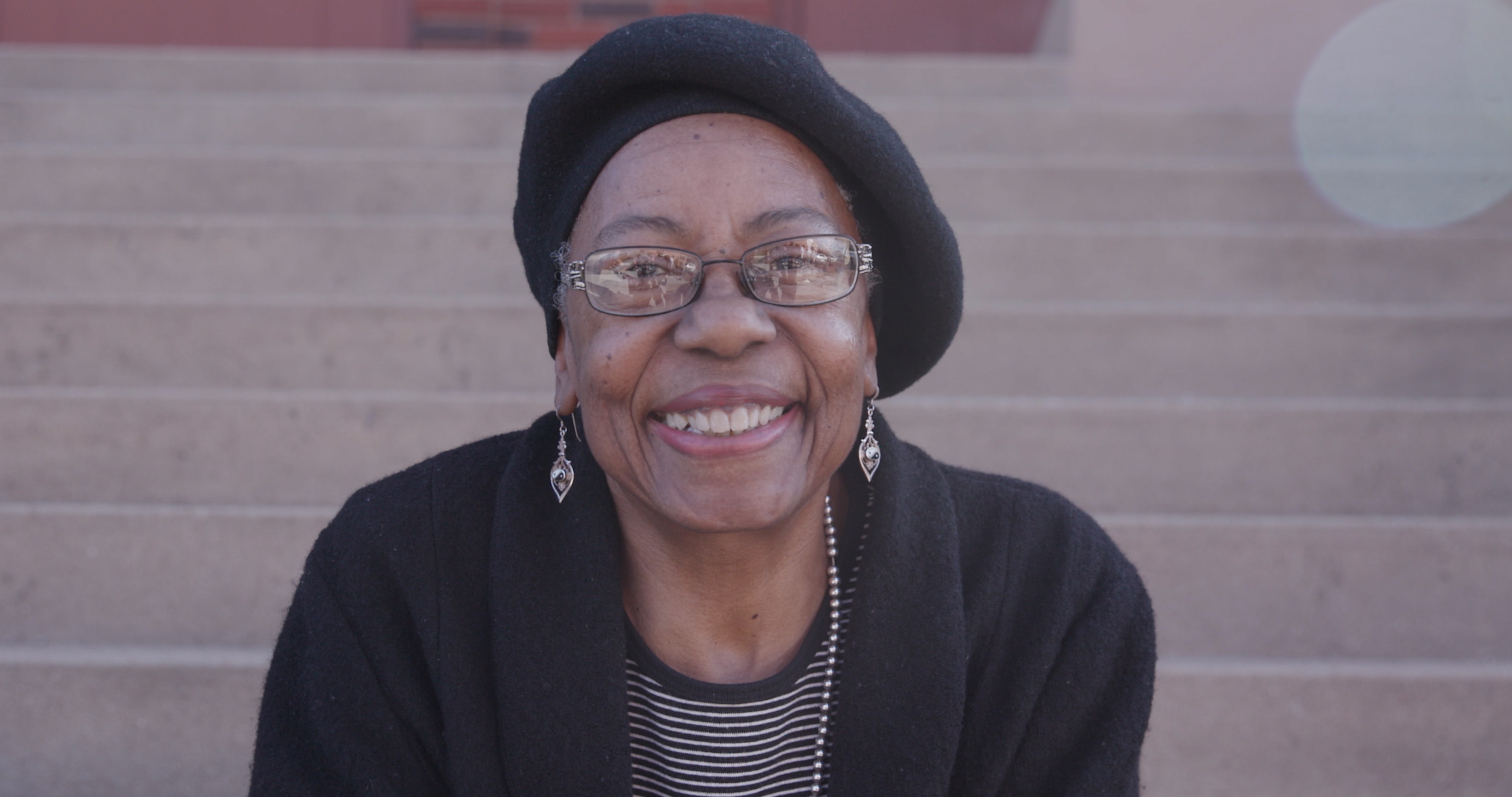 Woman smiling wearing beanie and glasses